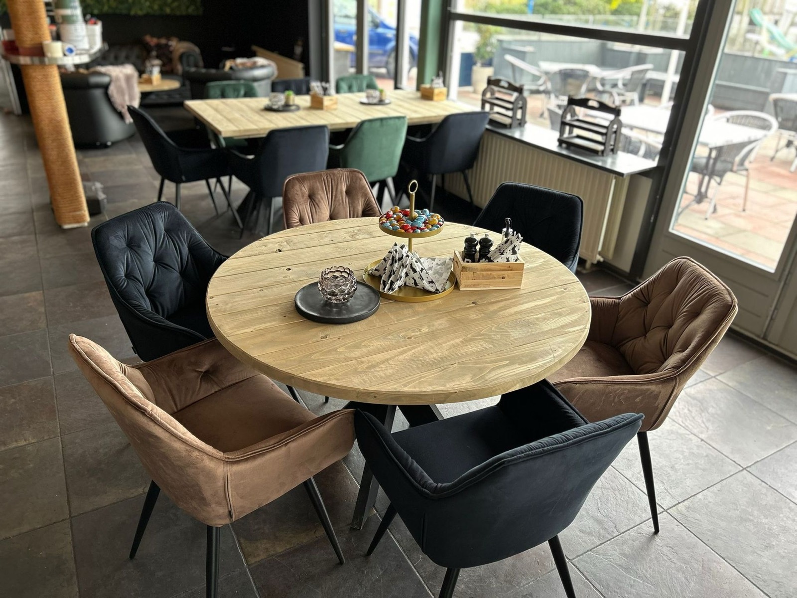 Ronde houten tafel met velours stoelen in cognac, zwart en groen